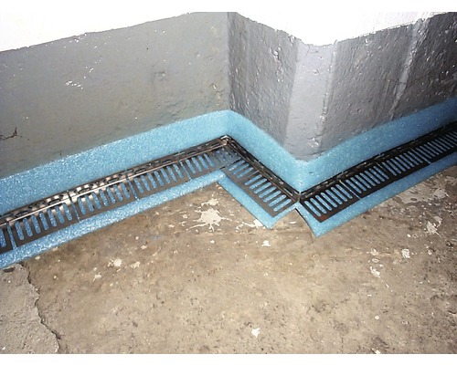 Metalen drainagegoot met isolatie tegen een kelderwand