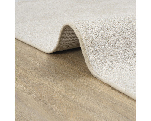 Gedetailleerde weergave van een beige tapijt op een houten vloer