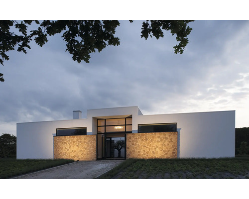 Modern huis met natuurstenen gevel en grote ramen.