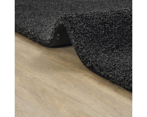 Gedetailleerd aanzicht van een grijs tapijt met hoogpolig oppervlak op een houten vloer