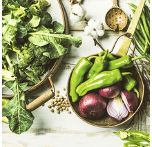 Stilleven met verse groenten, waaronder broccoli, paprika''s en uien, gerangschikt in kommen en op een houten oppervlak.