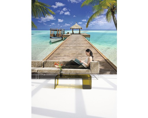 Wanddecoratie met tropisch strandmotief en vrouw op sofa