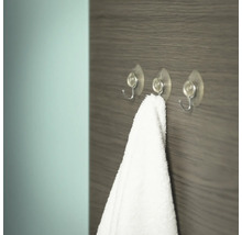 Drie transparante haken met zuignap en een witte handdoek aan een houten wand