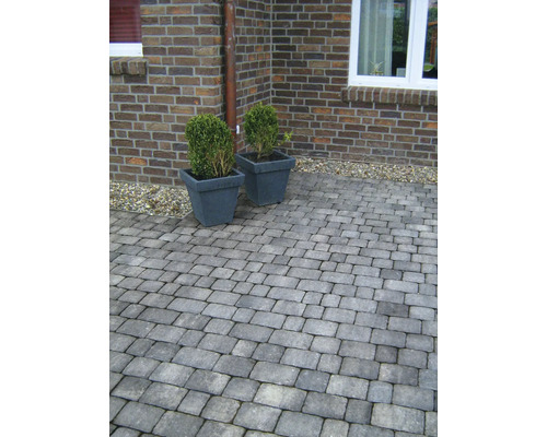 Buitenkant met straatstenen en twee plantenbakken voor een bakstenen muur.