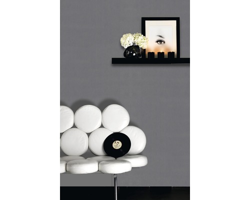 Scene met een witte stoel, vinylplaat, wandplank met decoratie en een portret aan een grijze muur