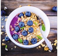 Muesli met bosbessen en munt in een kom met een lepel