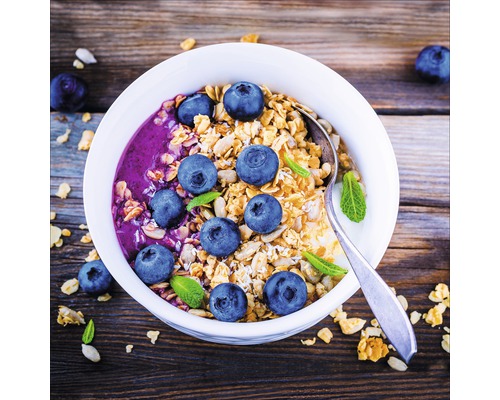 Muesli met bosbessen en munt in een kom met een lepel