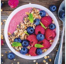 Kom met smoothie, bosbessen, frambozen en muesli op een houten tafel