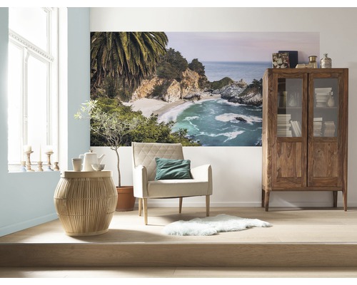 Woonkamer met fauteuil, bijzettafel, vitrinekast en muurschildering met strandmotief