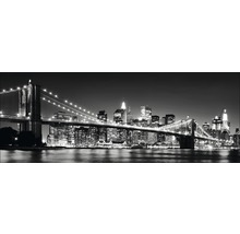 Zwart-witfoto van de Brooklyn Bridge en de skyline van New York bij nacht.