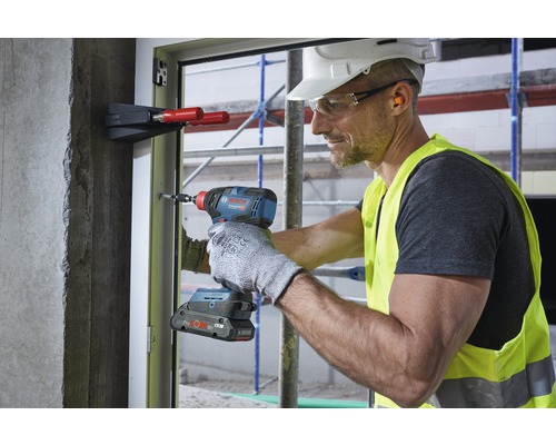 Ambachtsman gebruikt een accuslagschroevendraaier op een raamkozijn op een bouwplaats.