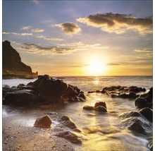 Een kustlandschap met rotsen in het water bij zonsondergang.