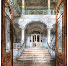 Interieurbeeld van een oud gebouw met trappen, zuilen en openstaande deuren.