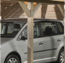 Een zilverkleurige auto staat onder een houten carport.