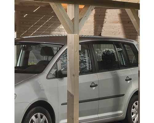 Een zilverkleurige auto staat onder een houten carport.