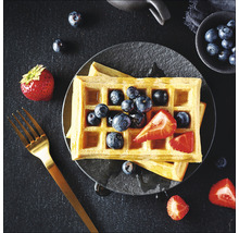 Wafels met bosbessen en aardbeien op een bord, plus een vork.
