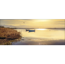 Zeegezicht met boten en riet in gouden licht