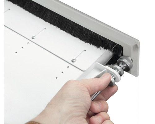 Detailopname van een hand die een borstelafdichting op een deur afstelt