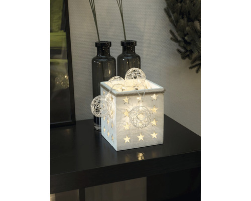 Decoratieve houten kist met sterren en lichtslingers op een tafel.