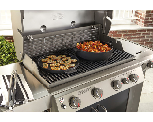 Weber gasbarbecue met gegrilde etenswaren en kookgerei op het grillrooster.