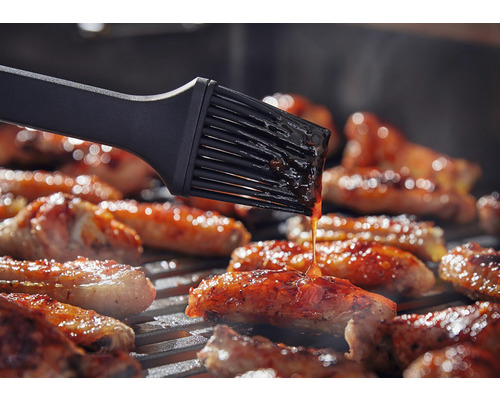 Grillborstel die vlees op een grill bestrijkt