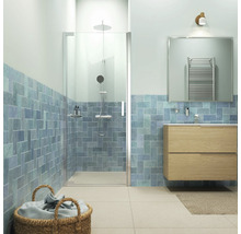 Lichte badkamer met douche, wastafel en blauw betegelde muren.