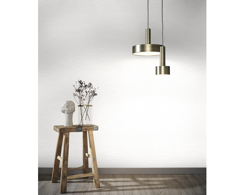 Scene met een hanglamp, een vaas met bloemen, een sculptuur op een kruk voor een behang.