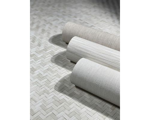 Drie rollen textielbehang op een vloer met visgraatmotief