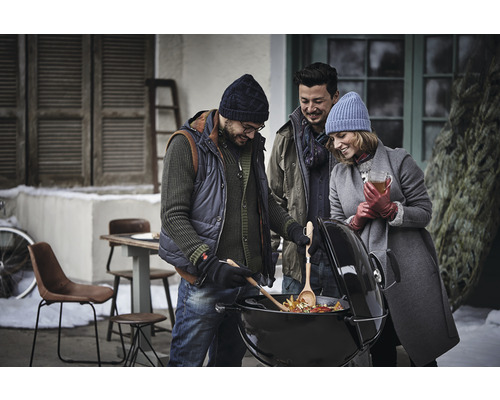 Een groep vrienden grilt groenten op een kogelbarbecue in de wintertuin.
