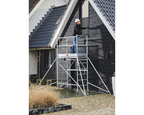 Man op een rolsteiger bezig met renovatiewerkzaamheden aan een huis