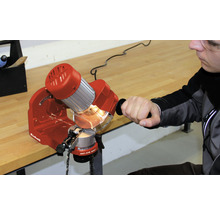 Een man slijpt een kettingzaag met een kettingzaagslijper van het merk Einhell.