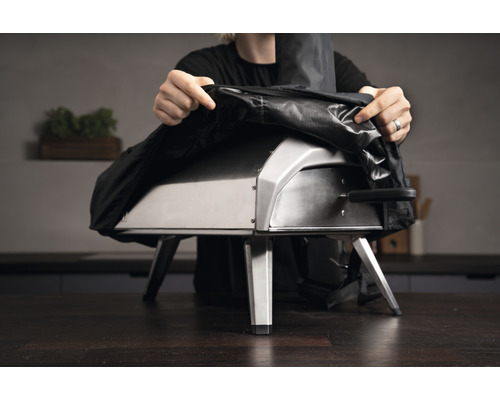 Persoon legt een hoes over een pizzaoven.