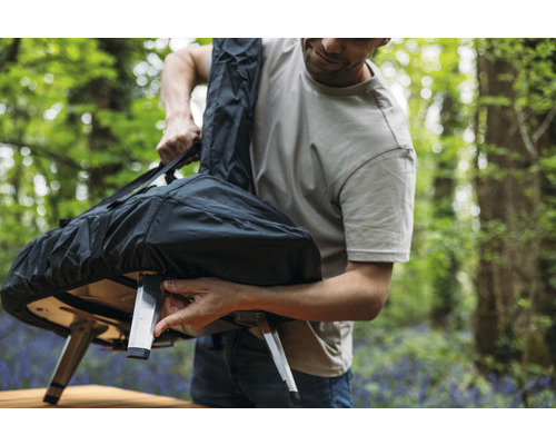 Man bergt pizzaoven op in een draagtas buitenshuis