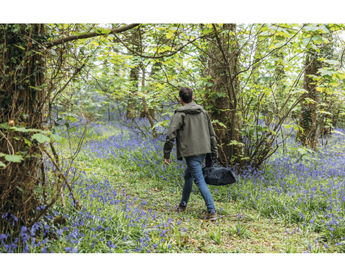 Man met tas loopt door een bos met bloeiende hyacinten