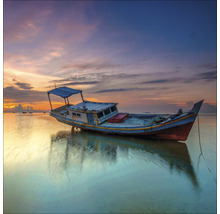 Een boot ligt in het water bij zonsondergang.