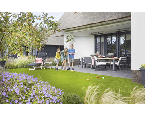 Familie speelt jeu de boules op kunstgras in de tuin met terras en tuinmeubelen