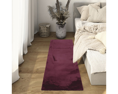 Slaapkamer met bed, gordijn en bordeauxrood vloerkleed