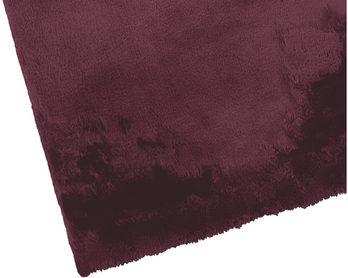 Detailopname van een bordeauxrood vloerkleed met zachte textuur