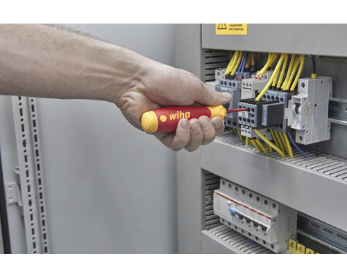 Hand schroeft met een Wiha schroevendraaier aan een zekeringkast.