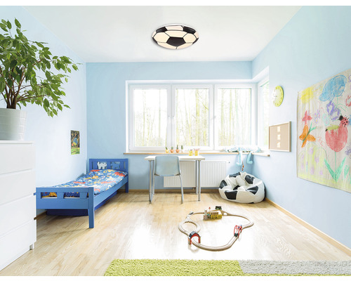 Kinderkamer met blauw bed, bureau, zitzak en voetbal plafondlamp.