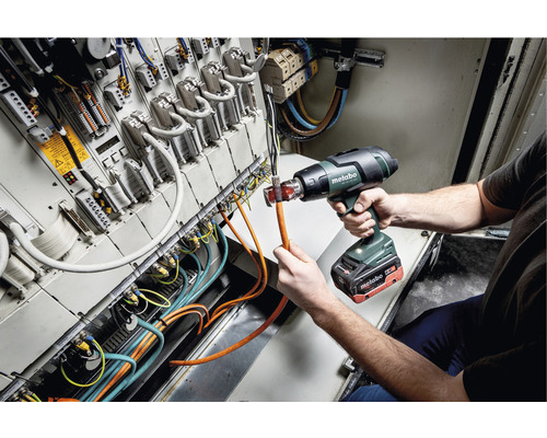 Een werknemer gebruikt een Metabo heteluchtpistool om een kabel in een schakelkast te bewerken.