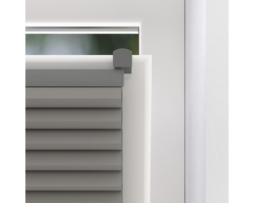 Detailopname van een grijs plisségordijn op een raam