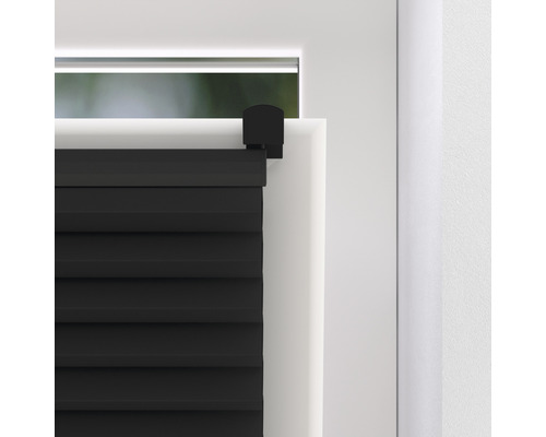 Detailopname van een zwart plisségordijn op een raam