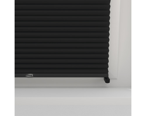 Close-up van een zwart plisségordijn op een raam