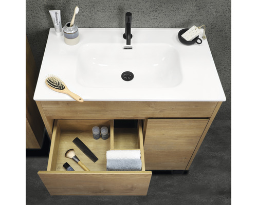 Houten wastafelonderkast met open lade en diverse badkamerartikelen op het oppervlak