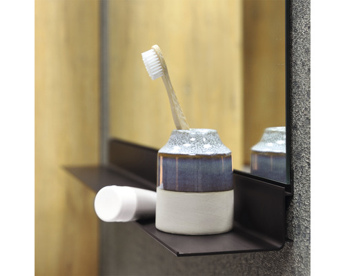 Badkamerscène met tandenborstelbeker, tandenborstel en cosmeticaproduct op een plank