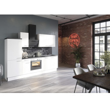 Moderne keuken met witte fronten, afzuigkap en eettafel in een loftachtige ruimte met bakstenen muur.
