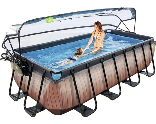 Rechthoekig zwembad met afdekking, ladder en houtlook, waarin een vrouw een kind helpt met zwemmen.