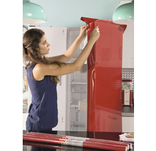 Vrouw beplakt koelkast met rode decoratiefolie in keuken.