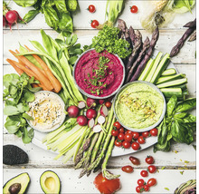 Groenteplateau met dips, wortelen, groene bonen, radijs, asperges, courgette, tomaten en avocado op een tafel